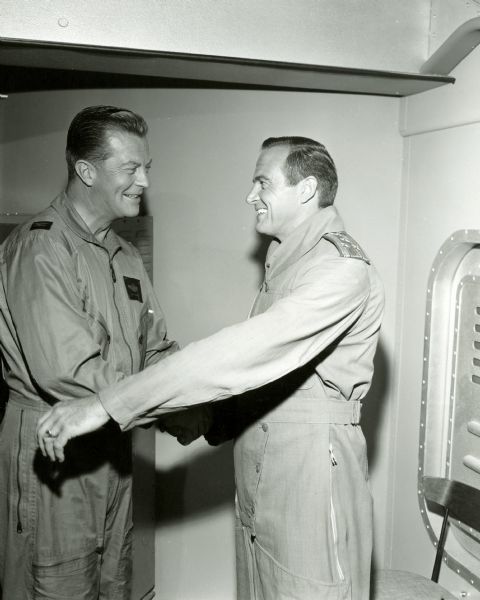 William Lundigan, as Colonel Ed McCauley, shakes hands with John Van Dreelen, who played Colonel Tolchek, a Soviet cosmonaut, in an episode of the television show <i>Men Into Space</i>. Both are dressed in flight suits.