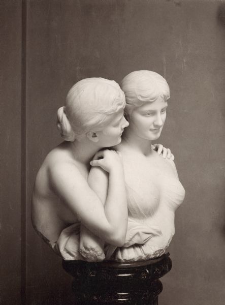 A bust sculpture in white marble of two women.