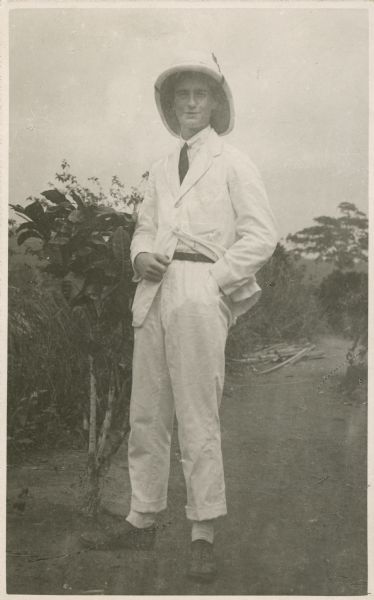 Noel Gillespie poses outdoors in a white suit and pith helmet.