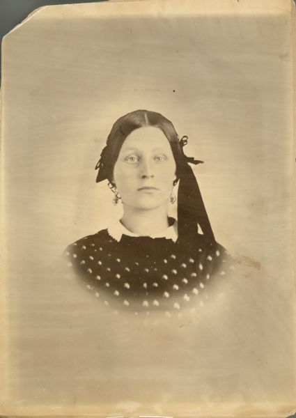 Head and shoulders vignetted portrait of Henrietta Waller, mother of Ida Schilling. She is wearing earrings and a ribbon in her hair.