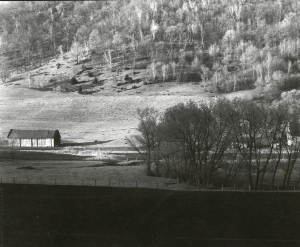 A view of Coon Valley at sunrise, including a wooden building, a fence, and trees.