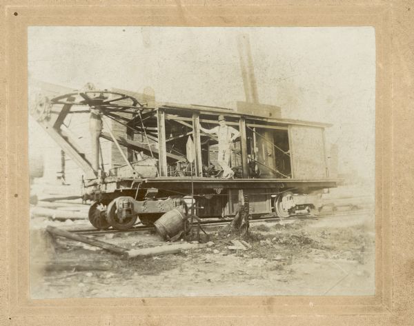 A man stands on a W & M railroad car known as a steam shovel.