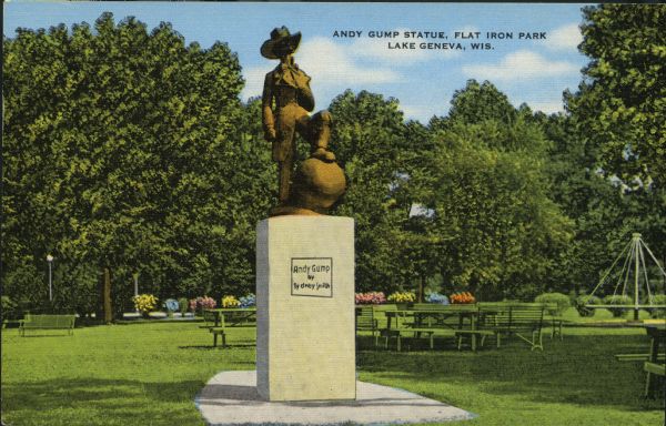 View of the Andy Gump statue in Flat Iron Park. Picnic tables, flowers, and trees are in the background. Caption reads: "Andy Gump Statue, Flat Iron Park, Lake Geneva, Wis."