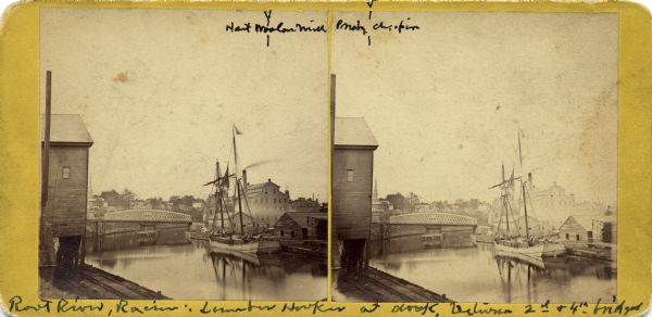 View of a lumber hooker ship at dock on the Root River. The 4th St. bridge spans the river at center. The Racine Woolen Mill is visible at right behind the ship (identified as Hart Woolen Mill on print). The building at left is also identified, but the writing is not legible.