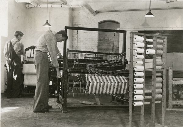 Two men weaving towels at looms.
