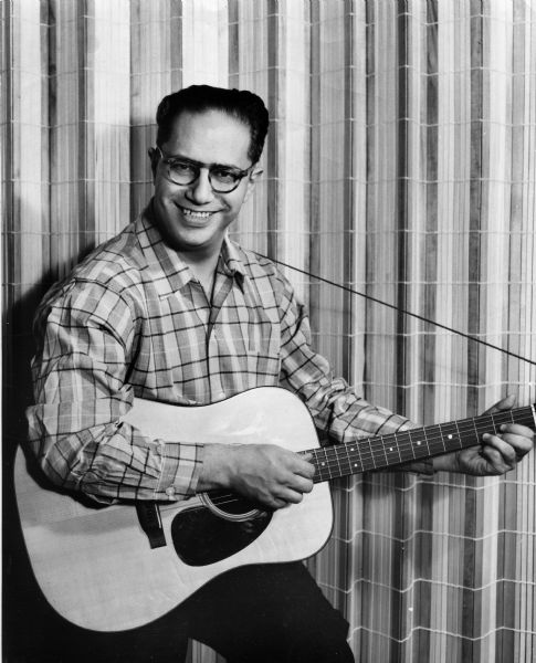 Portrait of singer and songwriter, Joe Glazer, holding a guitar.