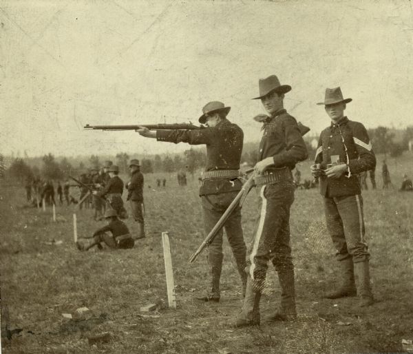 Wisconsin National Guard members at the firing range. In the foreground, one man fires as two others watch. Several similar groups can be seen in the background.