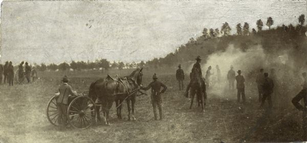 Wisconsin National Guard First Light Battery A from Milwaukee at Camp Douglas. A team of horses pulls a small wagon. There are trees and bluffs in the background.