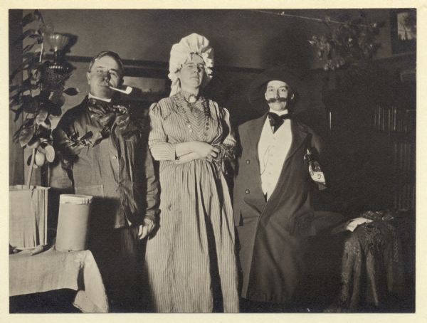 Ruben Gold Thwaites, Iva Welsh, and Mary Foster dressed as "Box and Cox" and Mrs. Bouncer from the 1840's comedy <i>Box and Cox</i>. They are at a costume party celebrating the 63rd anniversary of the State Historical Society of Wisconsin.