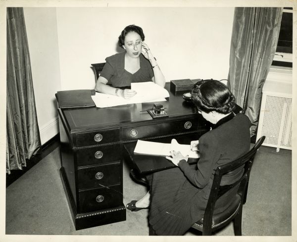 Irna Phillips sits at her desk dictating a letter to her secretary.