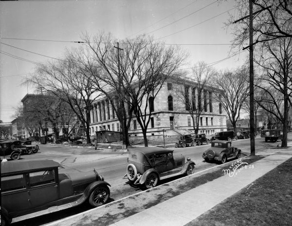 Madison Post Office at 215 Monona Avenue. View looking north of the front of nearly completed Post Office from across East Wilson Street, with automobiles parked along the curb in the foreground, and the Beavers Insurance Building at 119 Monona Avenue in the background.