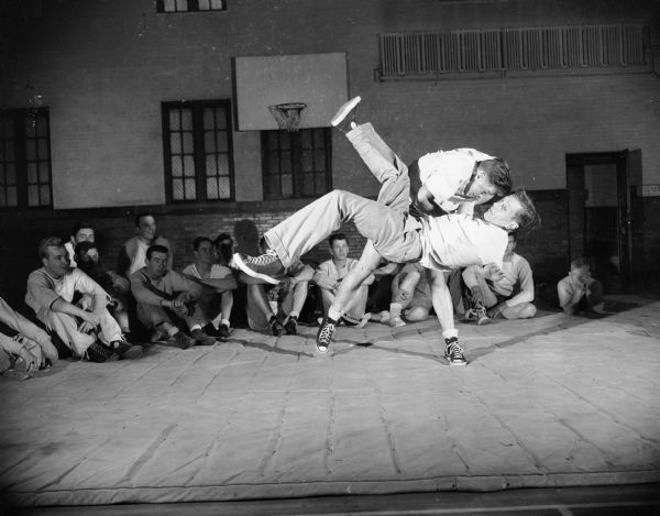 A man throws another man onto the mat during judo instruction at the YMCA.