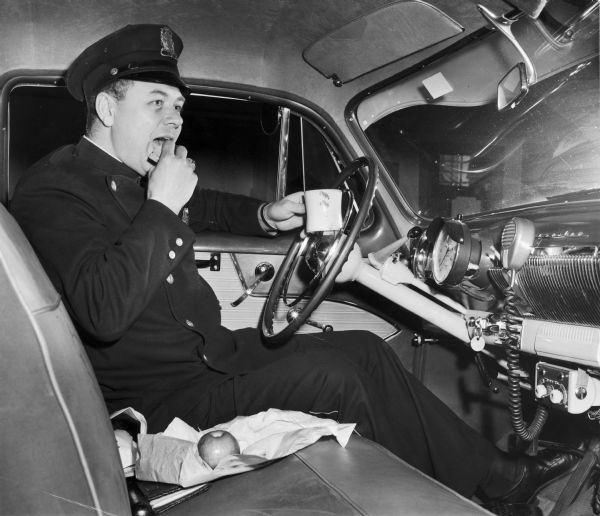 Patrolman Stanley Szczepanski eats lunch while sitting in his police car.