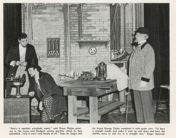 Actors portray I.M. Singer and George Zieber examining an early sewing machine.