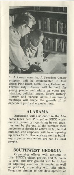 A white volunteer teaches a young African-American boy at a desk in front of a bookcase. Used in a brochure with the title, 'SNCC Summer 1965.'