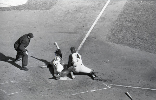 Elevated view of home plate umpire, Chris Pelekoudas, watching as Milwaukee Braves outfielder Gary Kolb slides into home ahead of the tag from Pirates catcher, Jerry May.