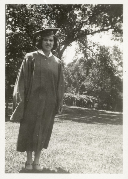 Full-length outdoor portrait of Alice Klusinski posing in her cap and gown on graduation day.