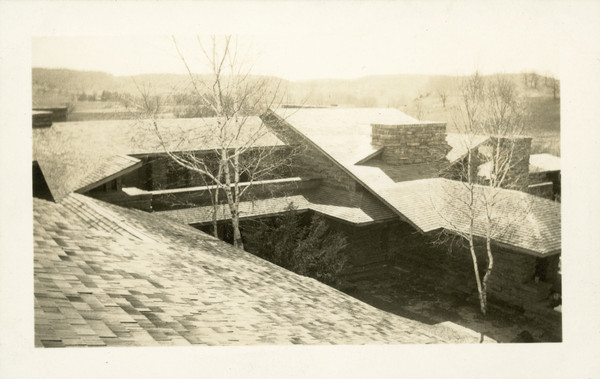 View from the roof of Taliesin, looking out over the house's rooftop and trees in the courtyard. The chimney on the far right is the chimney at Frank Lloyd Wright's bedroom. The terrace area behind the tree on the left was later closed.