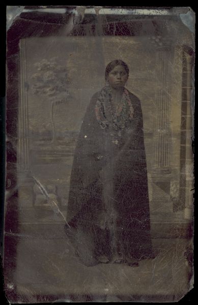 Full-length studio portrait of a woman standing in front of a painted backdrop.