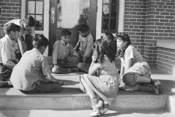 Group of children sitting outdoors on front steps.