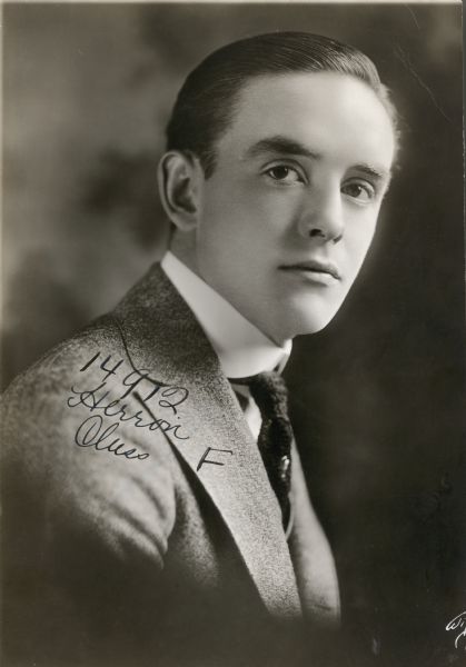 Quarter-length publicity portrait of actor Robert Harron. He is wearing a suit coat, tie and dress shirt. "14912 Herron ?? F" is written on his shoulder.