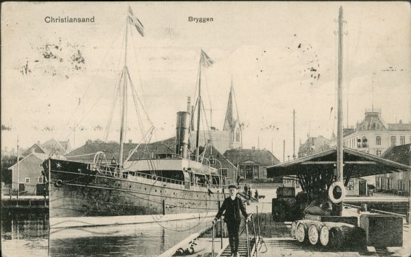 A postcard depicting a young man or teenager on a dock next to a steam ship.