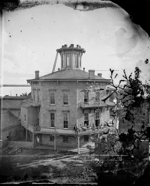 This building, on an entire block of Spaight and Brearly Streets with Lake Monona, was originally the governor's mansion for Leonard J. Farwell. The Farwell mansion was the first of two octagonal houses built in Madison. It then became a home for the orphans of Civil War soldiers and finally became the Monona Academy, a Norwegian Lutheran seminary. This building was levelled in 1895. A group of men, women and children are posing on the balcony on the right. Lake Monona is in the background on the left.