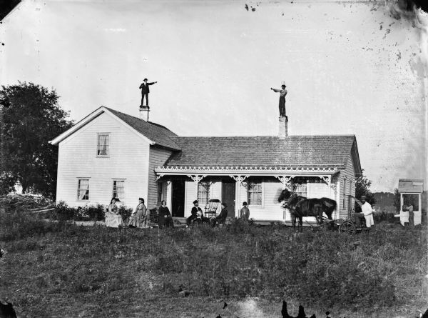 A unusual scene on an unidentified farmstead probably located near Pleasant Springs, Wisconsin. A family is posed in the yard of a frame house, as is usual in Dahl's photographs. On the right a man sits on a horse-drawn implement and further to the right a boy draws water from a well. However, totally divorced from this placid scene is a confrontation taking place on the roof of the house between two men posed on the chimneys. Although separated by twenty feet or so, they are apparently anxious to have a fist fight. This is a carefully posed photograph of uncertain but probably humorous meaning.