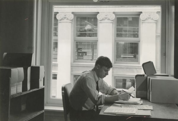Caption reads: "F. Gerald Ham, Wisconsin State Archivist, examining papers (posed re-enactment) in preparation of a guide to labor history research materials in the State Historical Society.
