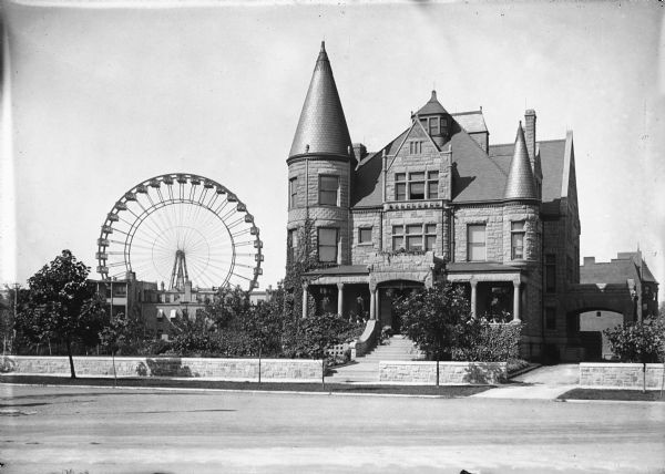 View of a large, stone residence with the first Ferris Wheel in the distance.