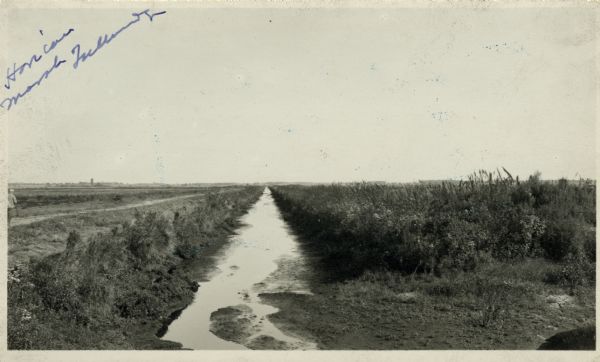 View of a drainage ditch in Horicon Marsh. A man is on a path along the left of the ditch.
