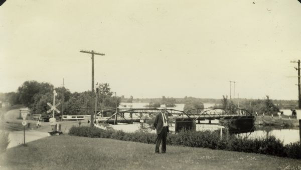 View looking north across the Highway 21 bridge at Necedah Lake. A man, likely a Resettlement Administration worker, poses in the grass in the foreground.