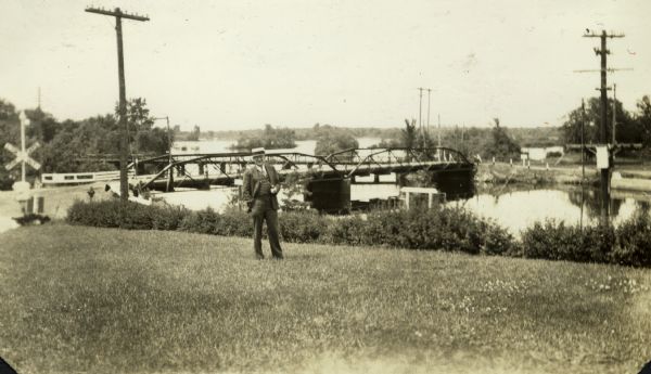 View looking north across the Highway 21 bridge at Necedah Lake. A man, likely a Resettlement Administration worker, stands holding a pipe in the foreground.
