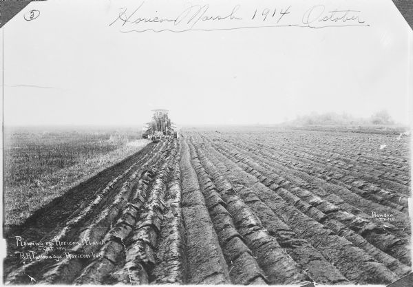 View of furrowed ground in Horicon Marsh and men on a tractor in the process of plowing a drained portion of the marsh.