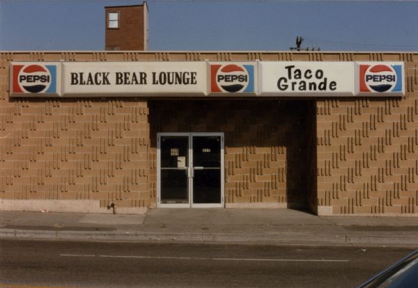 Exterior view from street of the Black Bear Lounge and Taco Grande at 310 North Frances Street. There are three Pepsi logos on the sign.