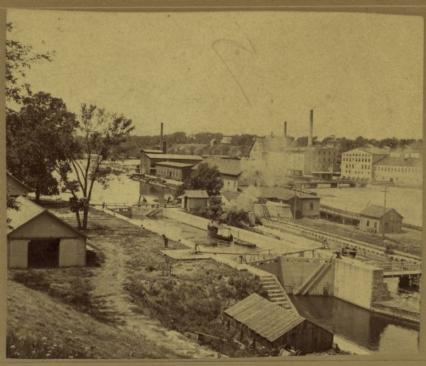 Elevated view of a lock at Appleton, with views of mills and other structures in the background.