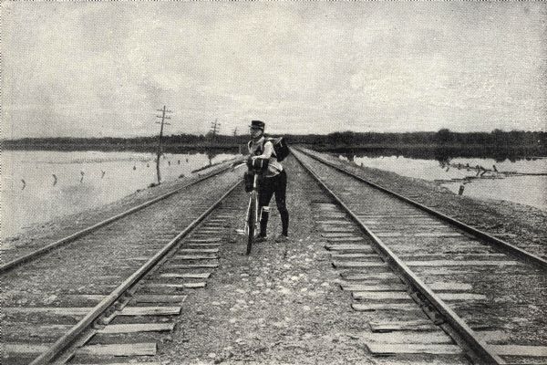 Frank G. Lenz posed with his bicycle between railroad tracks in the northeastern United States.
