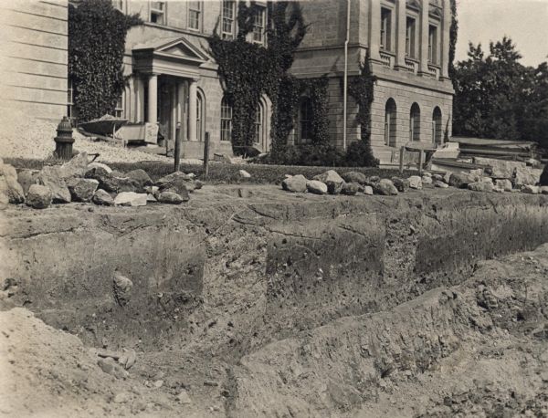 View of the excavation of two graves located on University Hill (now Bascom Hill). Main Hall (now Bascom Hall) can be seen in the background.