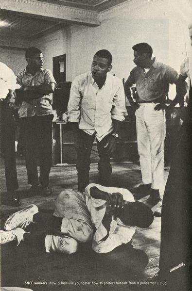 SNCC workers teach a young Danville man how to protect himself from a policeman's club.