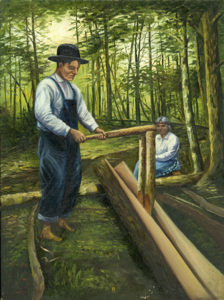 An Ojibwa man splits a cedar trunk with a wooden tool. The cedar is to be used to build the framework for a canoe. A woman is seated nearby.