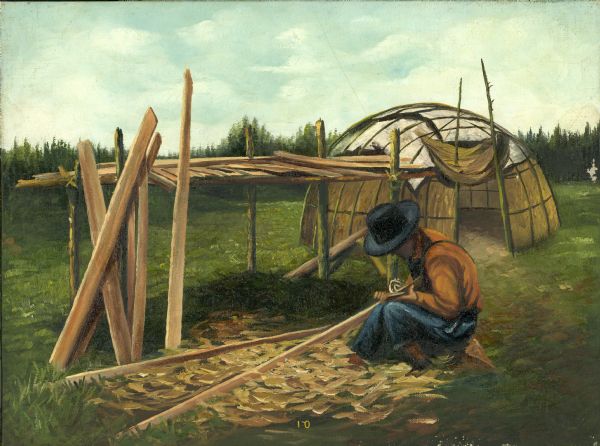 An Ojibwa Indian whittles strips of wood for the sides of a canoe under construction. In the background is a wigwam (or wetu). 