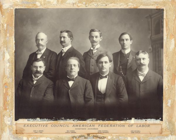 Group portrait in front of a painted backdrop of the Executive Council of the American Federation of Labor (AFL). Back row, left to right: John B. Lennon, Max Morris, James O'Connell, John Mitchell; front row, left to right: Thomas H. Kidd, Samuel Gompers, Frank Morrison, James Duncan.