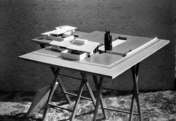 An architectural model of two houses for Broadacre City set up on a drafting table.