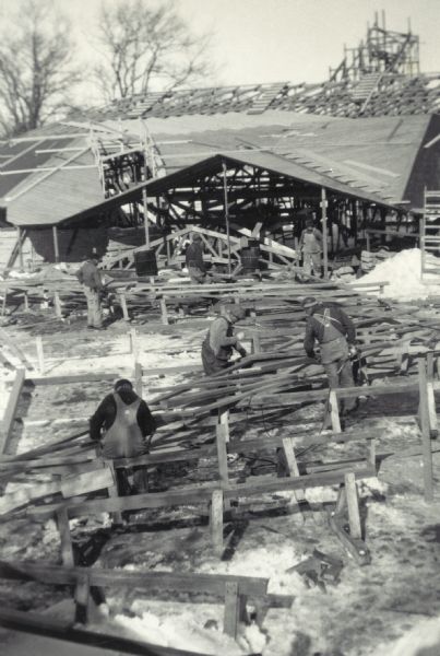 Elevated view of men working on trusses laid on sawhorses on the ground near the church.
