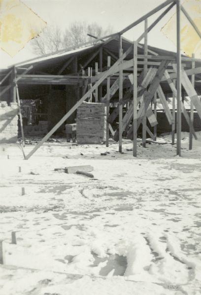 View across snowy ground towards a section of the church under construction, including sections of stone walls.