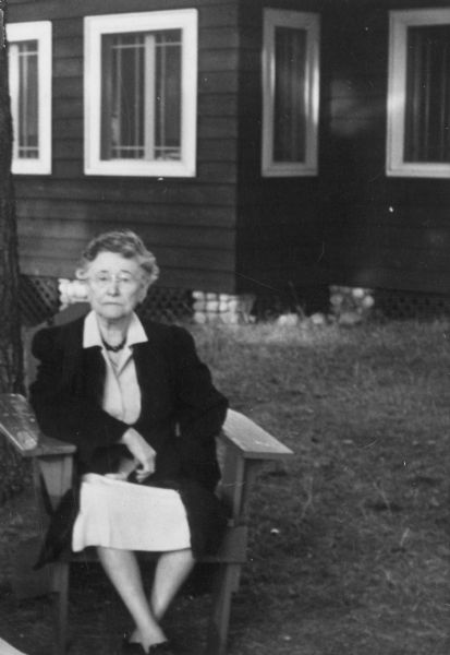 Helen Gilbert Van Vechten seated outdoors in front of a cottage. Mrs. Van Vechten was the co-founder of the Philosopher's Press in Wausau.