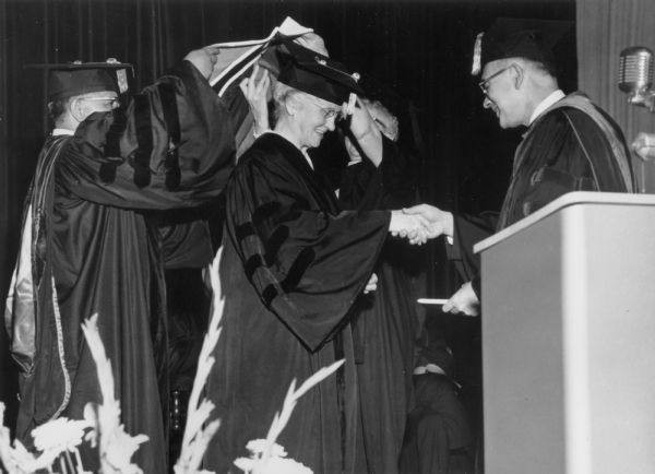 Professor Helen C. White shakes a man's hand at the 1965 commencement ceremony for Grinnell College.