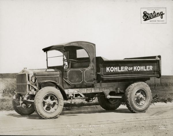 Driver's side view of truck parked on road, with the name "Kohler of Kohler" painted on the side. The Sterling Motor Trucks logo is printed at the top right of the photograph.