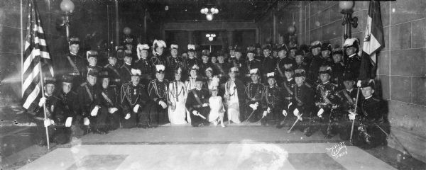 Group portrait of Independent Order of Odd Fellows (I.O.O.F.) Madison Canton in full uniform in the Wisconsin State Capitol, with Betty Livesey.
