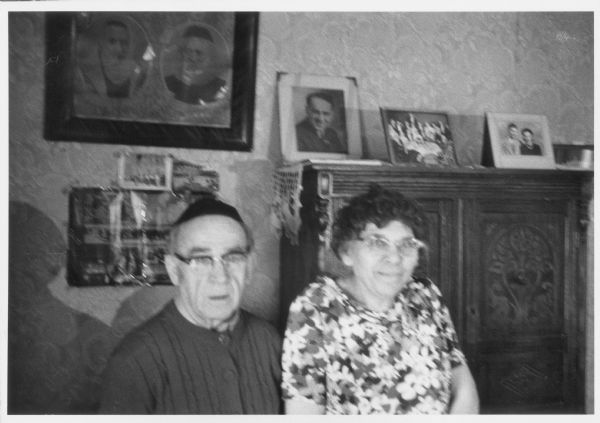 Rabbi Alex Hyatt and his wife Bernice Hyatt. Framed portraits are on the wall behind them.